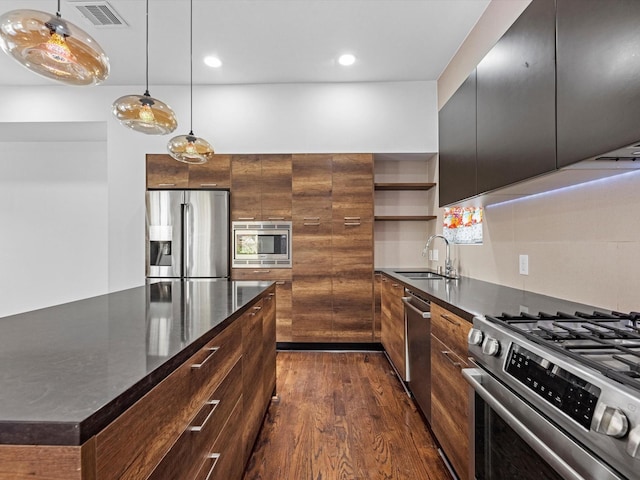 kitchen with stainless steel appliances, sink, pendant lighting, dark hardwood / wood-style floors, and a kitchen island