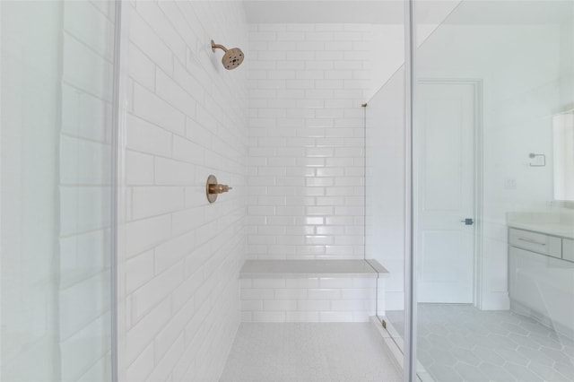 bathroom featuring a tile shower, vanity, and tile patterned floors