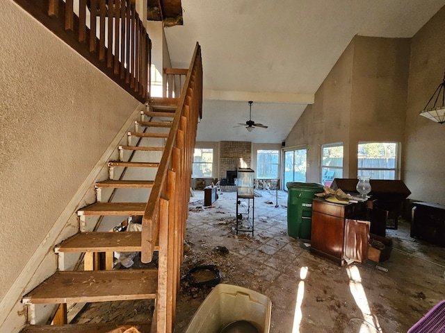 stairs featuring ceiling fan, a fireplace, and high vaulted ceiling