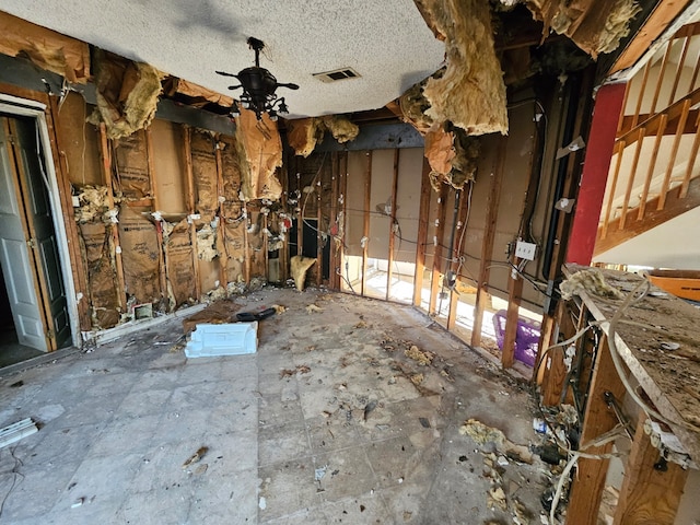 miscellaneous room with ceiling fan and a textured ceiling