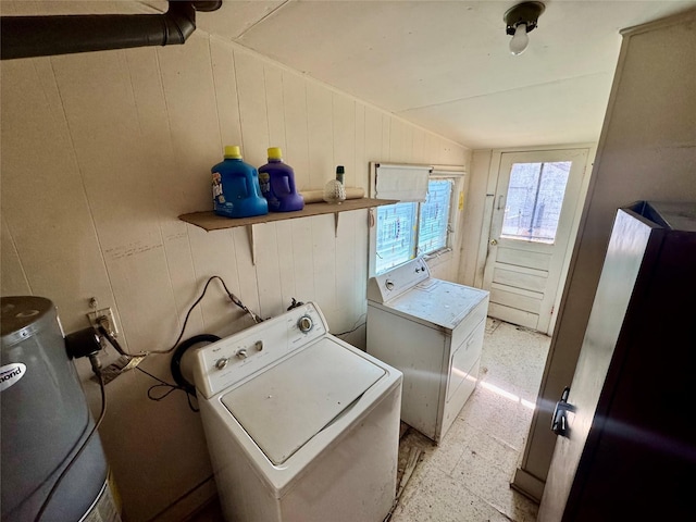 clothes washing area with washer / clothes dryer and wood walls