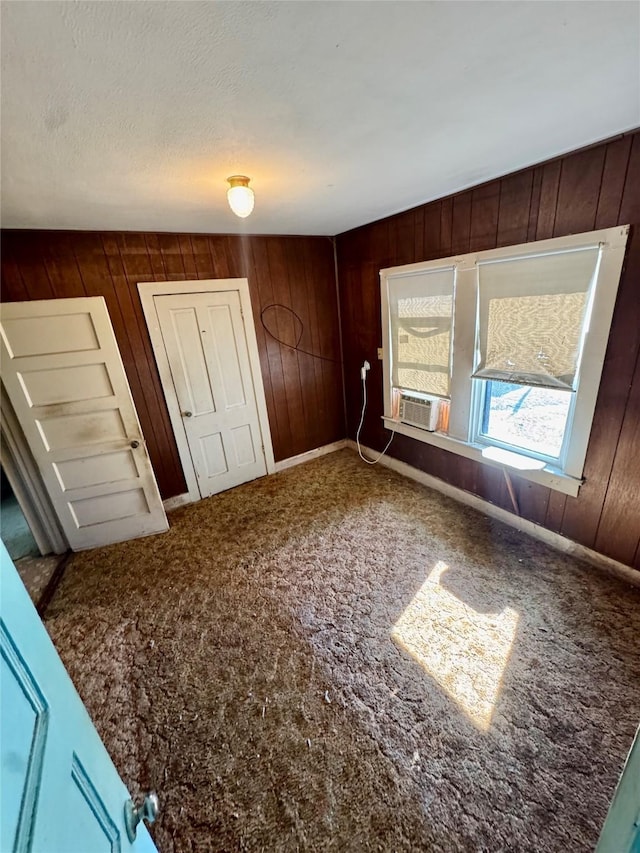 unfurnished bedroom featuring wood walls and carpet