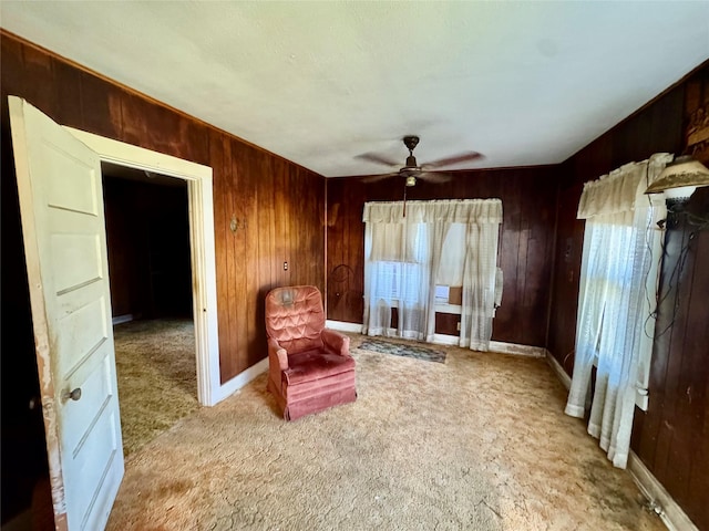 sitting room with a wealth of natural light, carpet floors, ceiling fan, and wooden walls