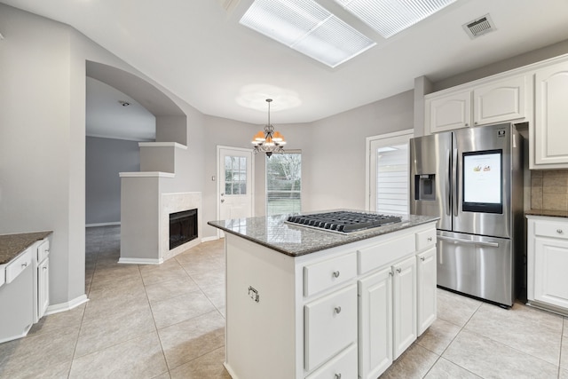 kitchen featuring hanging light fixtures, stainless steel fridge, white cabinetry, and a center island