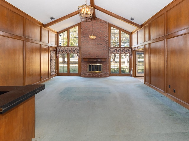 unfurnished living room featuring beam ceiling, light carpet, a chandelier, and a brick fireplace