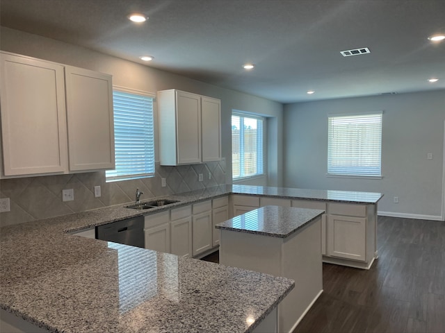 kitchen with kitchen peninsula, light stone countertops, sink, dishwasher, and a center island