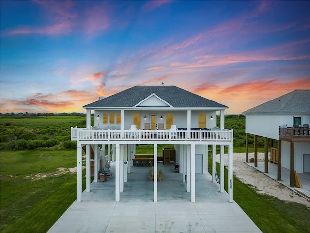 beach home with a carport, a balcony, covered porch, and a lawn