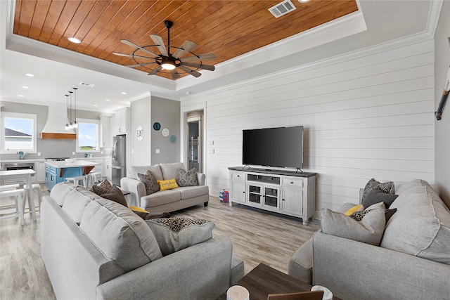 living room featuring wood walls, light hardwood / wood-style floors, a raised ceiling, and wood ceiling