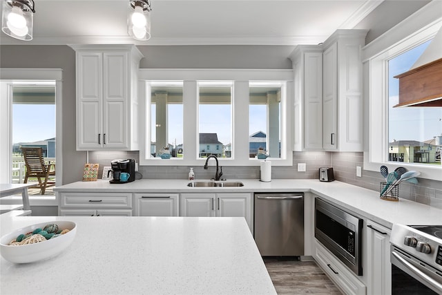 kitchen with crown molding, white cabinetry, sink, and stainless steel appliances