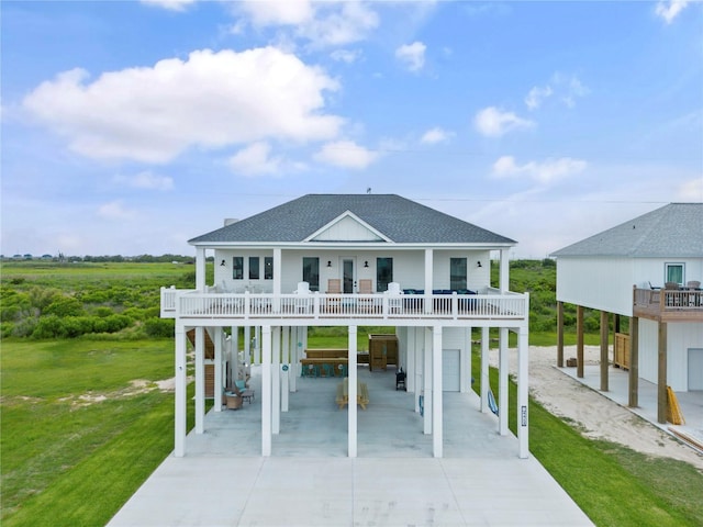 coastal inspired home with a carport, a balcony, and a front yard