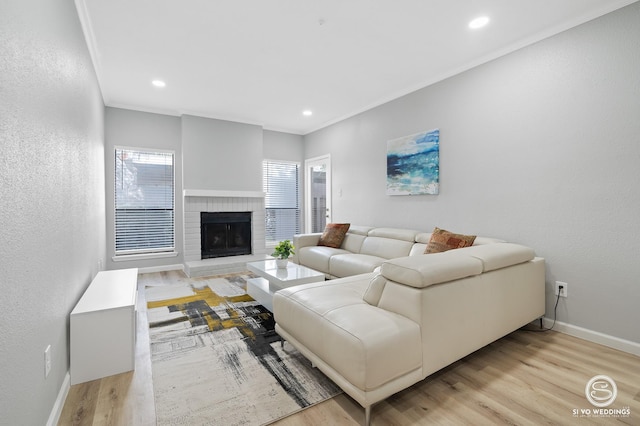 living room with ornamental molding, light hardwood / wood-style floors, and a brick fireplace