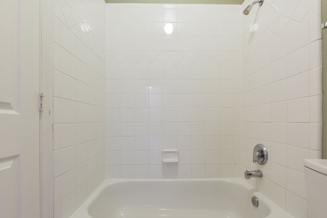 bathroom with toilet and tiled shower / bath