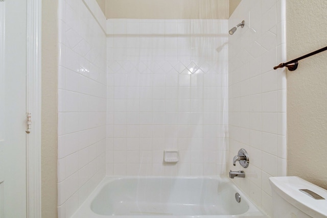 bathroom featuring toilet and tiled shower / bath