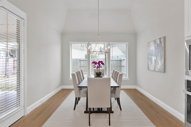 dining area with vaulted ceiling, light hardwood / wood-style floors, and a notable chandelier