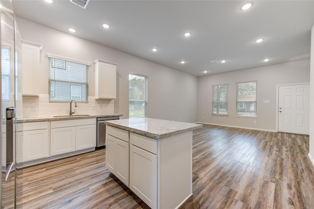 kitchen featuring light wood-type flooring, stainless steel dishwasher, sink, white cabinets, and a center island