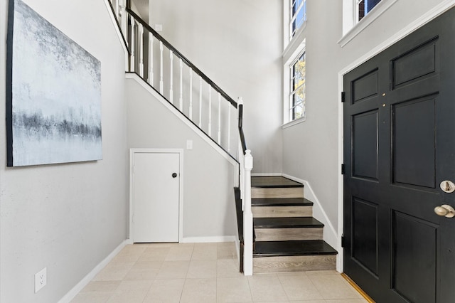 foyer entrance featuring light tile patterned flooring and a towering ceiling