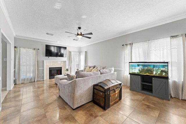 living room with ceiling fan, ornamental molding, a textured ceiling, and light tile patterned floors