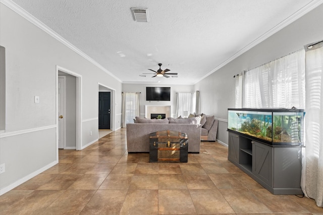 living room featuring ceiling fan, crown molding, light tile patterned floors, and a textured ceiling