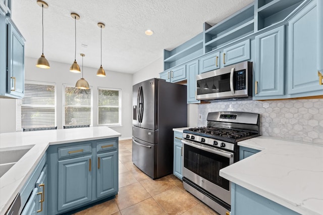 kitchen featuring light tile patterned flooring, pendant lighting, blue cabinets, light stone counters, and stainless steel appliances