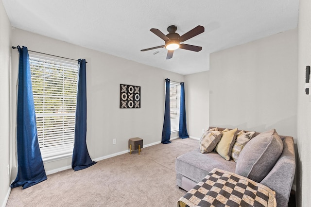 living area with ceiling fan and light colored carpet