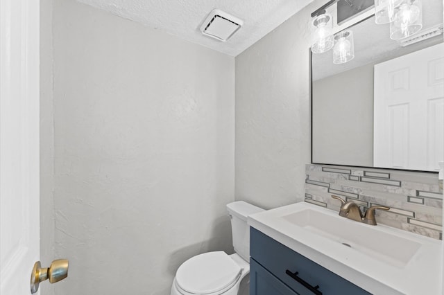 bathroom with tasteful backsplash, vanity, a textured ceiling, and toilet