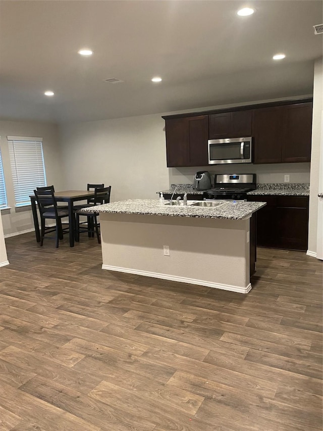 kitchen featuring a kitchen island with sink, dark hardwood / wood-style flooring, and stainless steel appliances