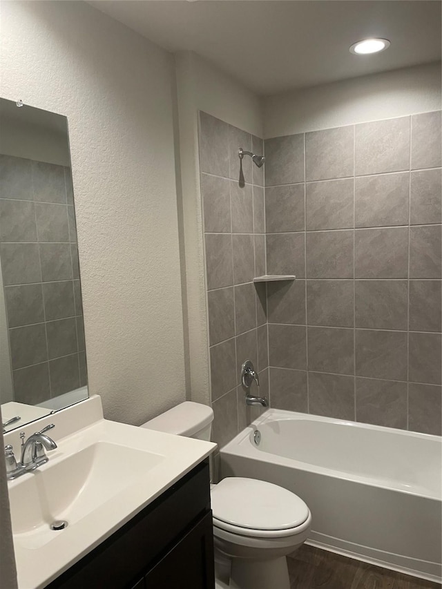 full bathroom with toilet, tiled shower / bath, vanity, and hardwood / wood-style flooring