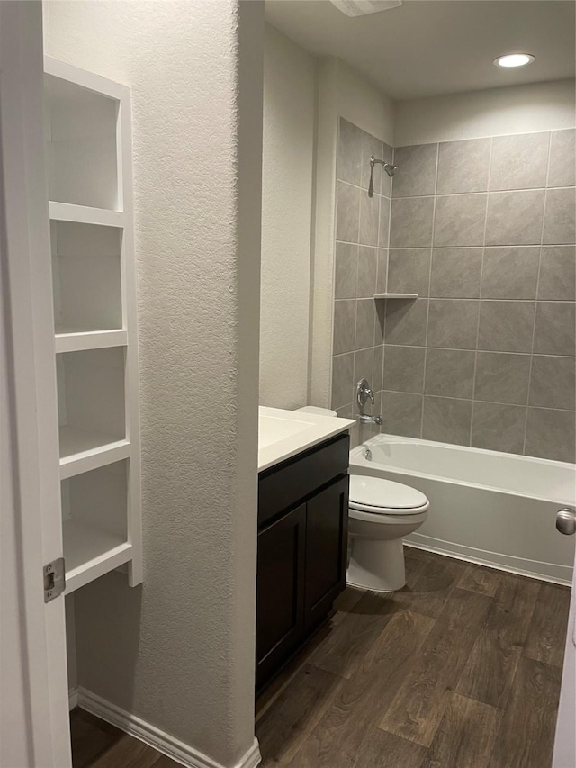 full bathroom featuring toilet, tiled shower / bath, hardwood / wood-style floors, and vanity