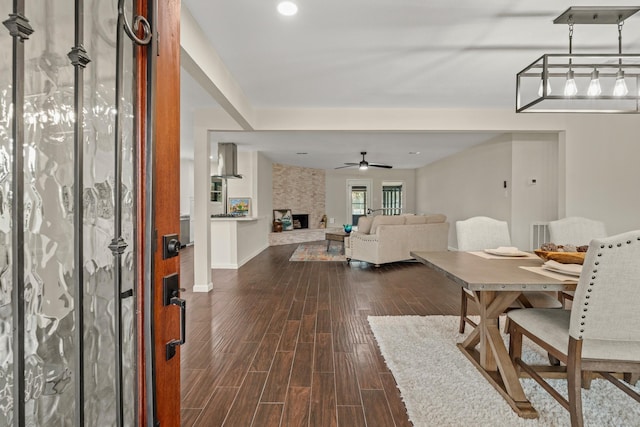 unfurnished dining area featuring ceiling fan, a fireplace, and dark hardwood / wood-style floors