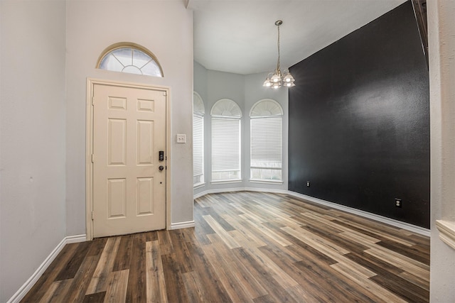 entryway featuring dark hardwood / wood-style flooring, a towering ceiling, and a chandelier