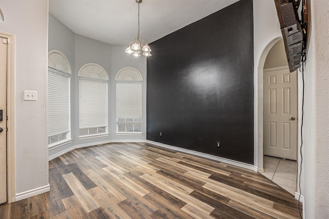 unfurnished dining area featuring a notable chandelier and hardwood / wood-style flooring