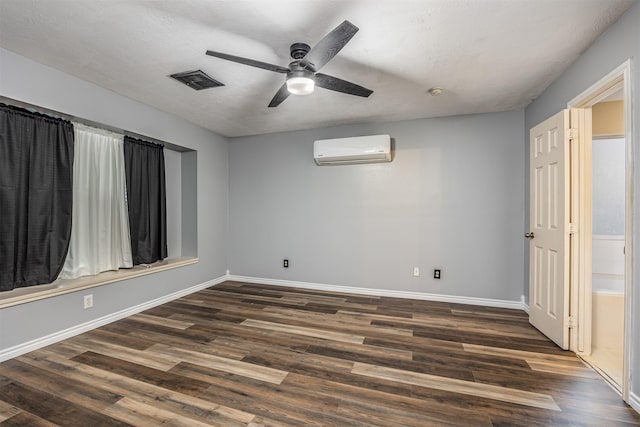 spare room featuring dark wood-type flooring, a textured ceiling, ceiling fan, and a wall mounted air conditioner