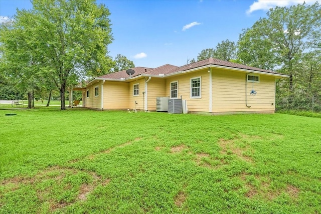 rear view of house featuring central AC and a lawn