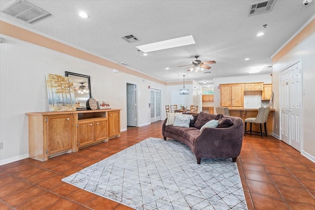 living room featuring a textured ceiling, a skylight, dark tile patterned floors, and ceiling fan