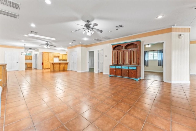 unfurnished living room featuring a skylight, crown molding, tile patterned flooring, and ceiling fan