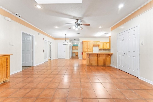 unfurnished living room with ceiling fan, crown molding, and light tile patterned flooring