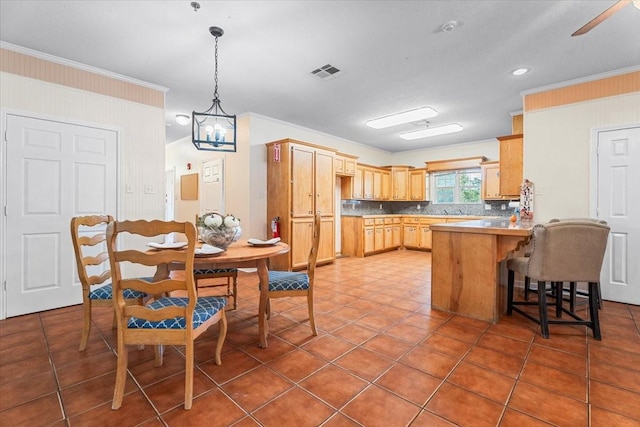 kitchen with kitchen peninsula, a kitchen breakfast bar, light brown cabinetry, and ornamental molding