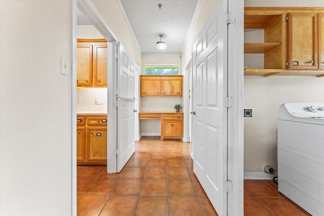 corridor featuring tile patterned floors, washer / clothes dryer, a textured ceiling, and ornamental molding