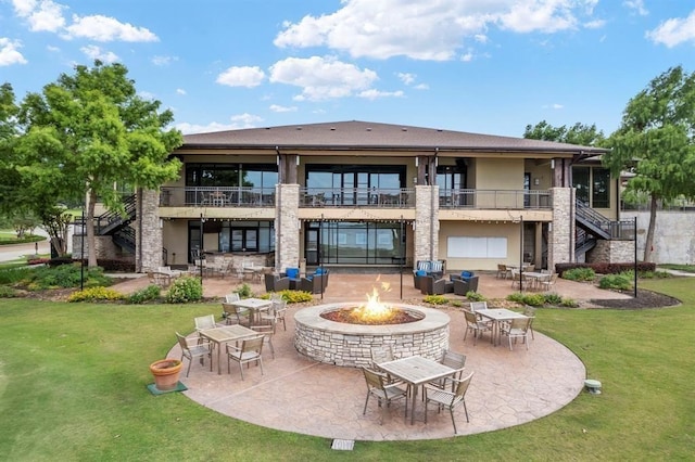 back of property featuring a yard, a balcony, a fire pit, and a patio area