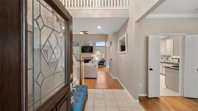 foyer entrance with light tile patterned floors, ceiling fan, ornamental molding, and sink