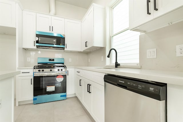 kitchen with light tile patterned floors, appliances with stainless steel finishes, white cabinetry, and sink