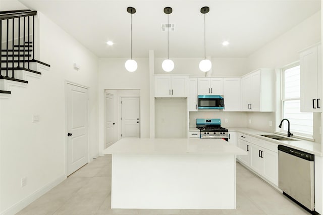 kitchen featuring appliances with stainless steel finishes, white cabinets, a center island, and sink