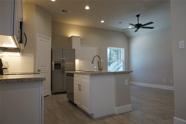 kitchen with white cabinets, light stone countertops, and an island with sink