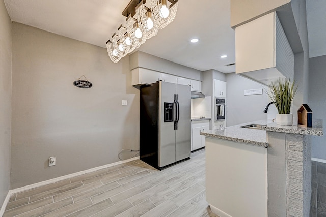 kitchen featuring light stone countertops, white cabinetry, sink, stainless steel appliances, and pendant lighting