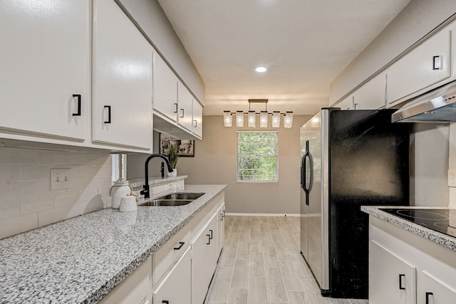 kitchen with stainless steel refrigerator, sink, light stone counters, light hardwood / wood-style flooring, and white cabinets