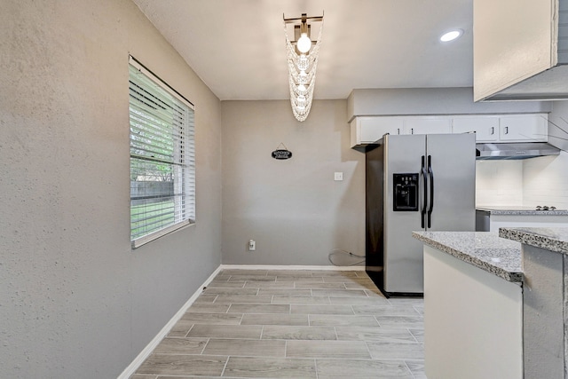 kitchen with light stone countertops, stainless steel refrigerator with ice dispenser, backsplash, and white cabinetry