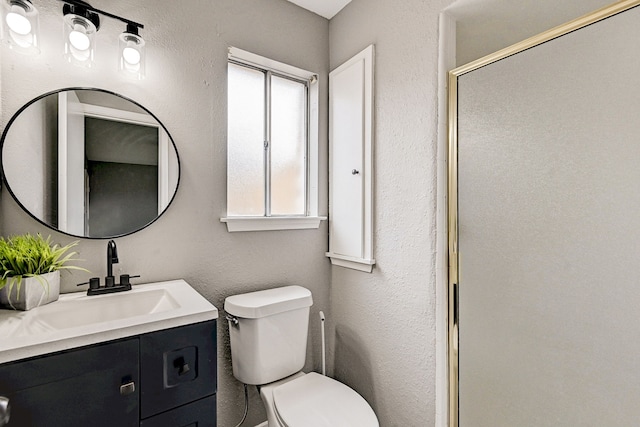 bathroom with vanity, a healthy amount of sunlight, toilet, and a shower with shower door