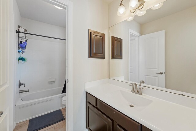 full bathroom featuring tile patterned floors, vanity, a notable chandelier, washtub / shower combination, and toilet