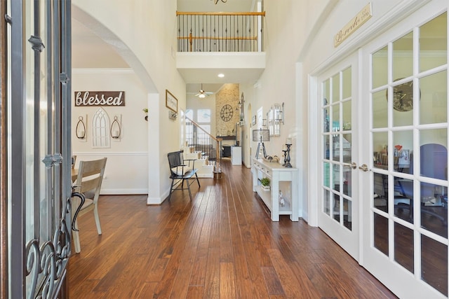 foyer entrance featuring dark wood-type flooring, french doors, crown molding, ceiling fan, and a towering ceiling