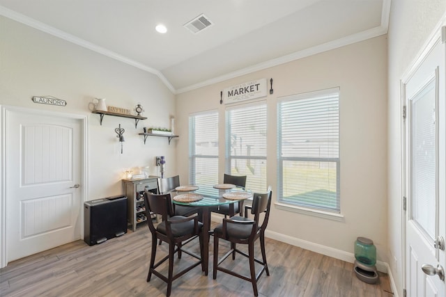 dining room with light hardwood / wood-style flooring, vaulted ceiling, and ornamental molding